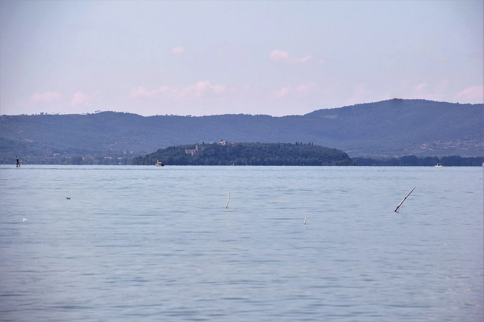 L'Isola Maggiore vista dal lago Trasimeno, con le colline sullo sfondo e un battello davanti all'isola